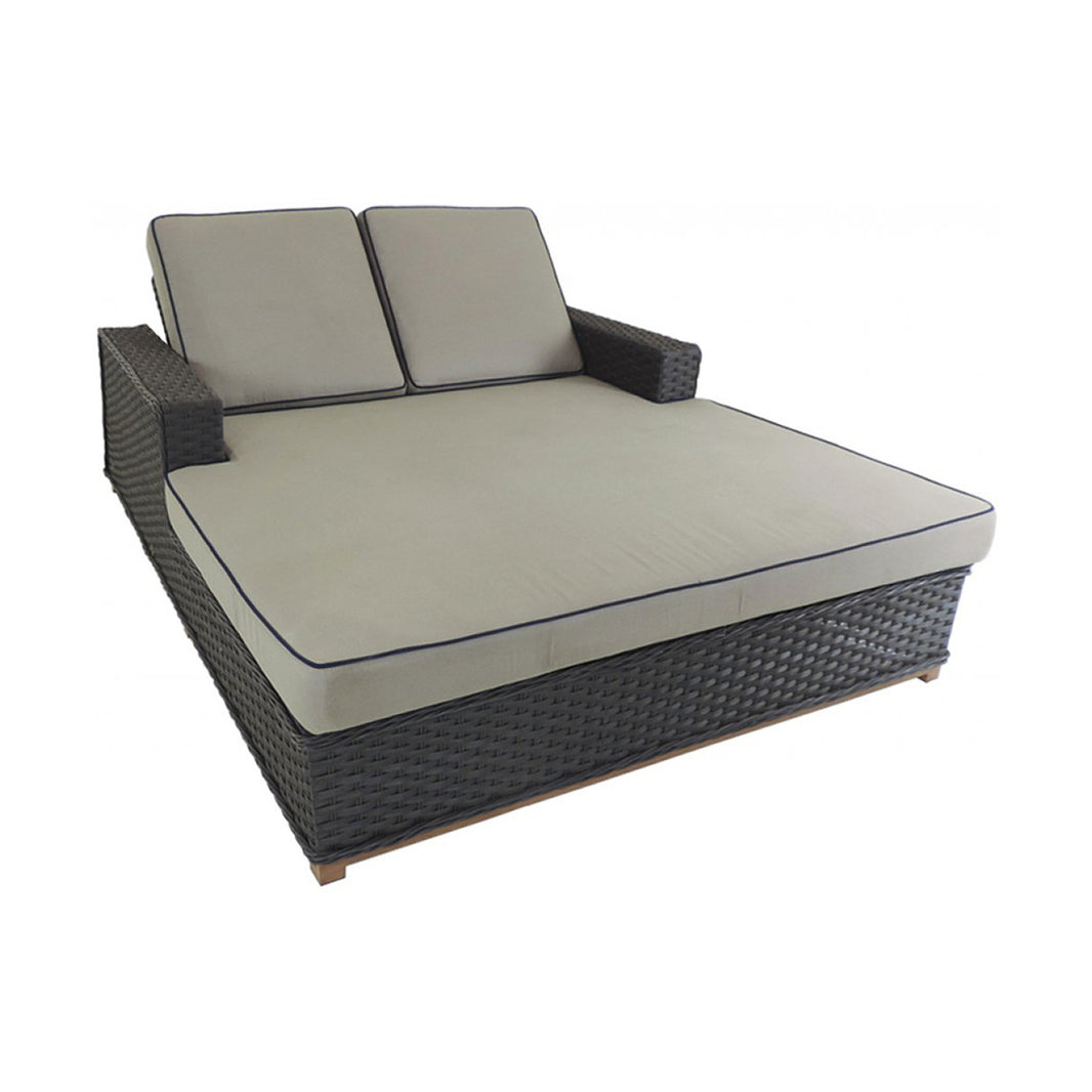 Wicker outdoor daybed with beige cushions on a white background